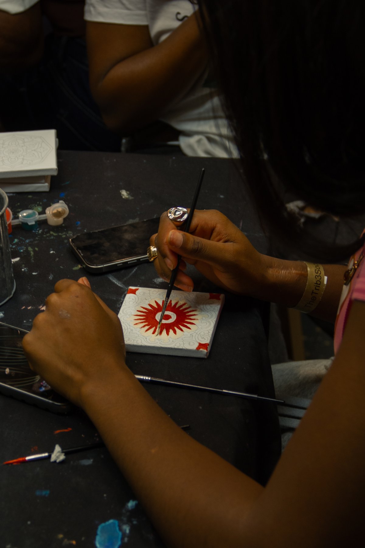 A hand painting a red flower
